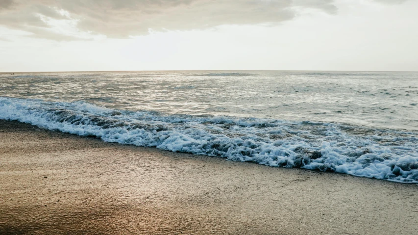 a wave crashing on the sand on an empty beach