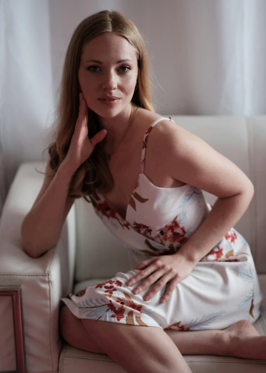 a woman sitting on a white couch wearing a dress