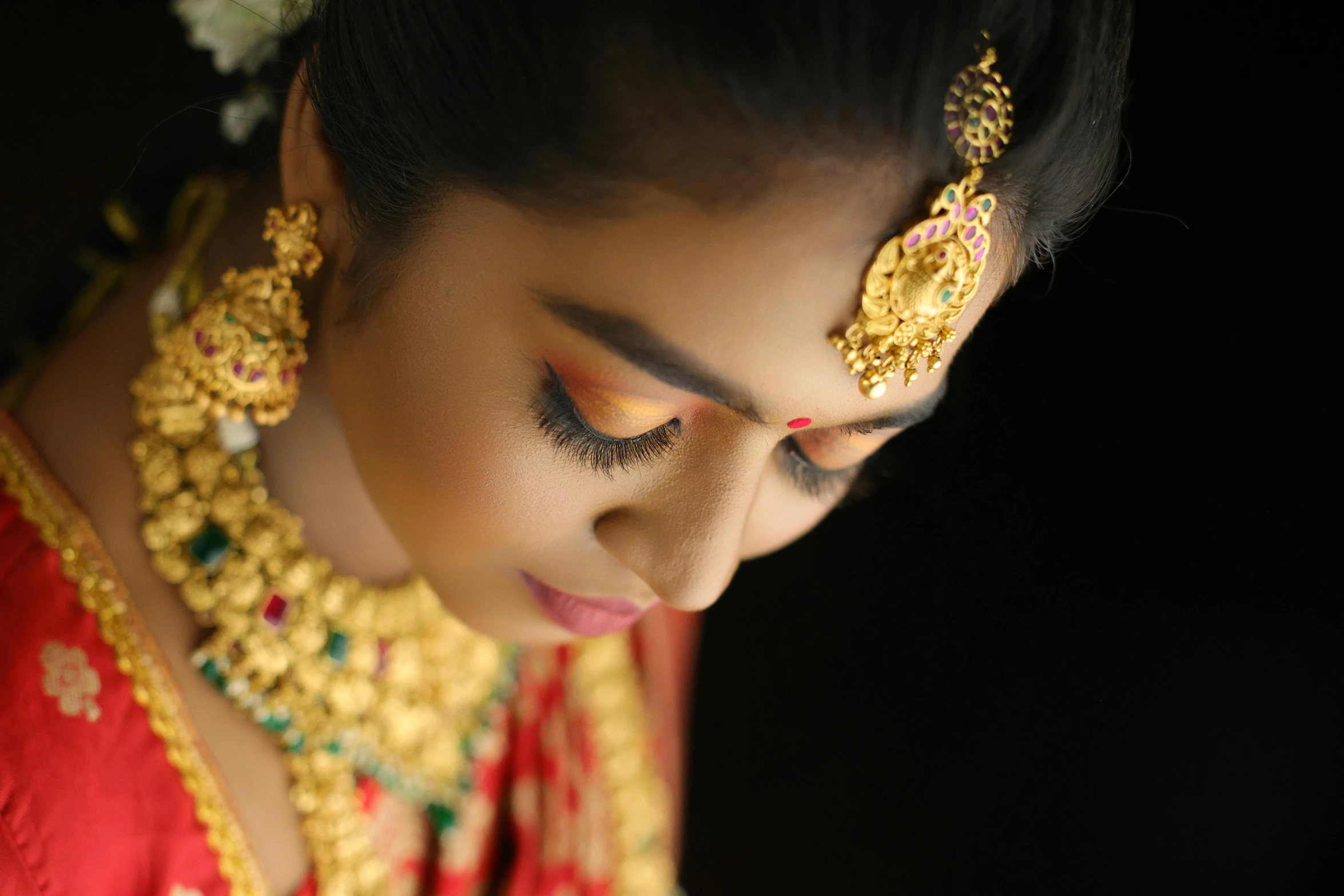 the woman is wearing gold jewelry and looking down