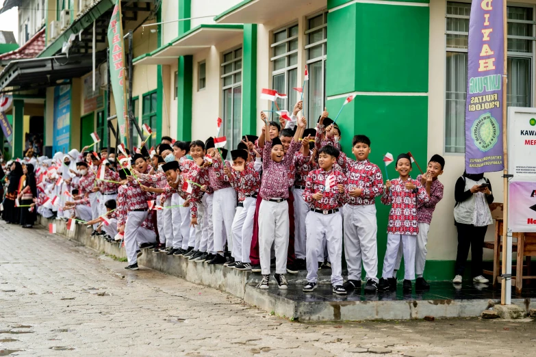 the group of boys are holding a flag outside a building