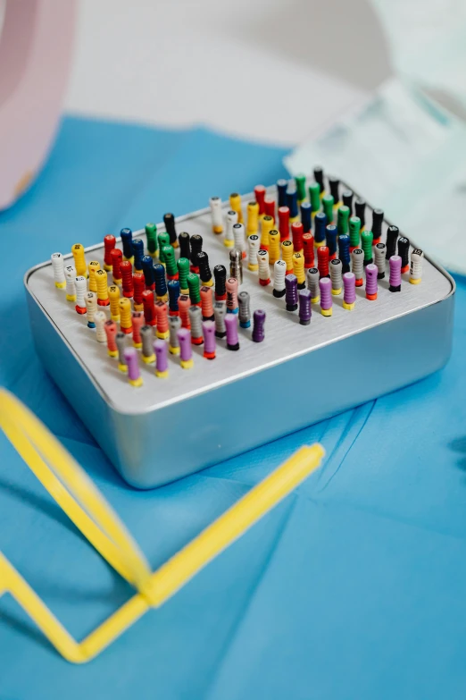 colorful colored nails and a yellow brush in a container on a blue table