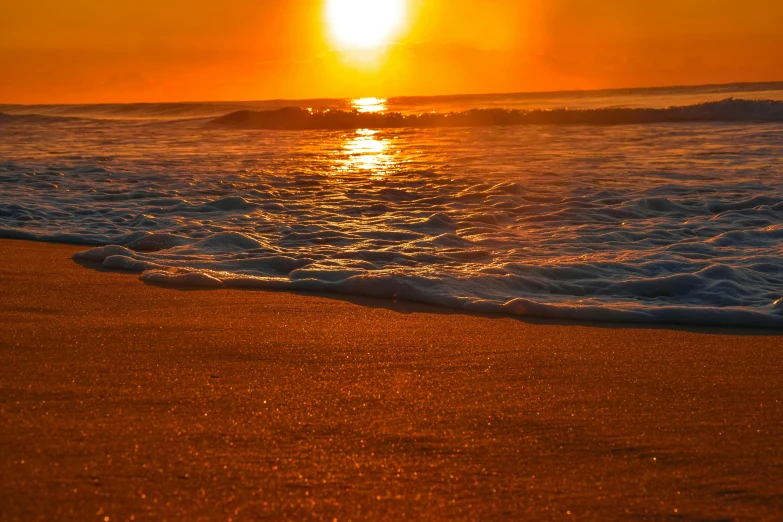 the sun rising behind a horizon at a beach