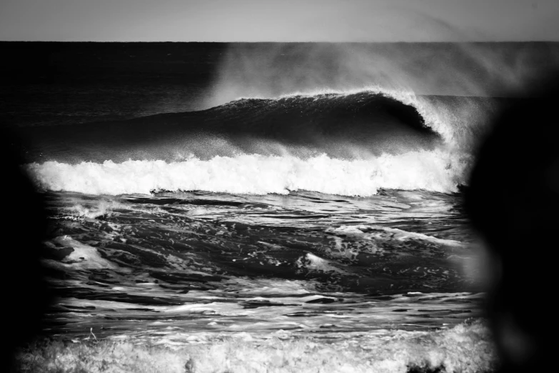 a person taking a picture at the bottom of a large wave