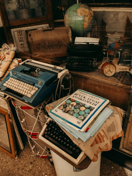 a desk that has old typewriters and boxes on it
