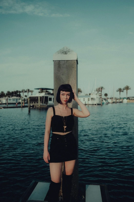 a woman in a black skirt standing on a dock