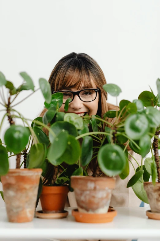 a woman with glasses sitting behind many plants