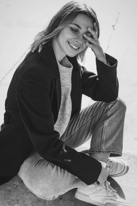 a beautiful young lady sitting on the ground wearing jeans