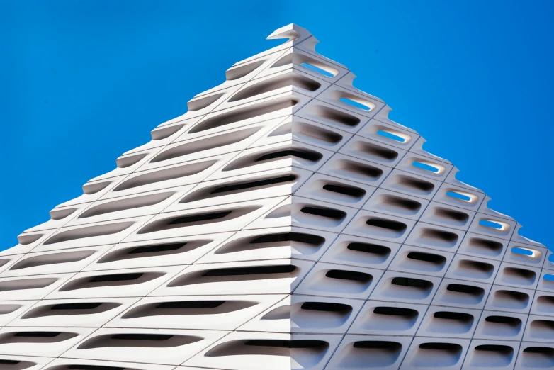 a triangle shaped building with lots of windows against a blue sky