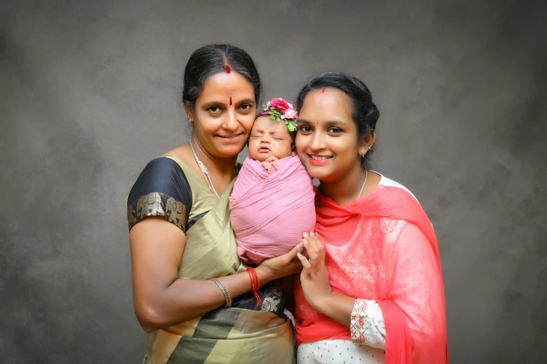 a woman holding a baby while standing next to another woman