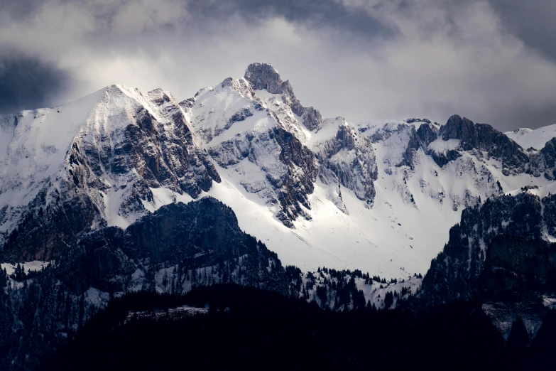 there is a mountain covered in snow under a cloudy sky