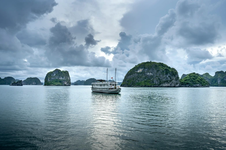 a large boat sits in the water near two small islands