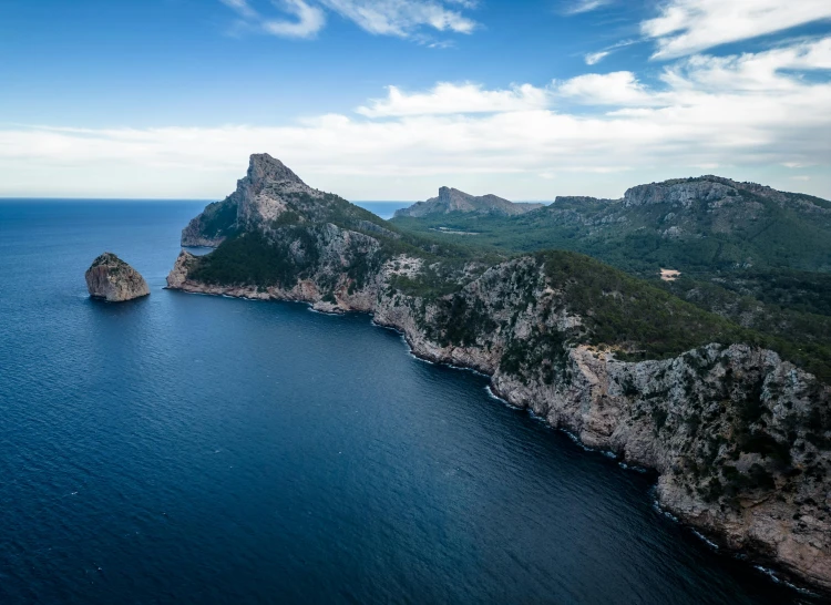 an island in the middle of the ocean surrounded by mountains