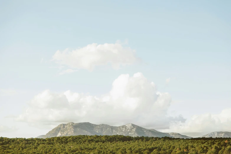 there is a mountain in the background with many clouds above