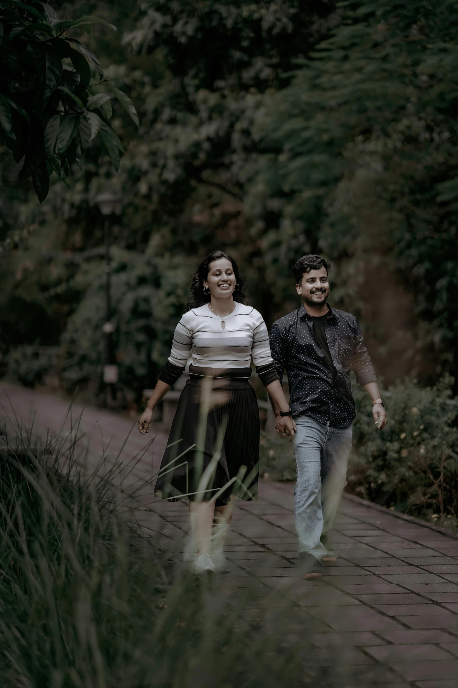 two people holding hands are walking on a paved path