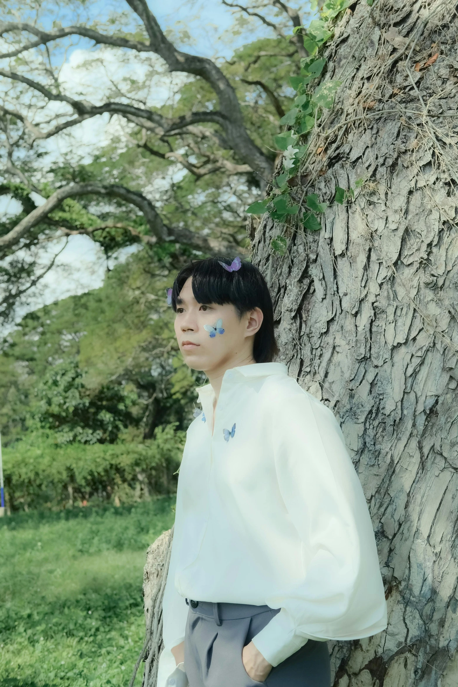 woman with makeup on face standing in front of tree