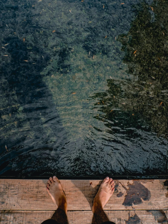 a person standing on a wood walkway next to a body of water