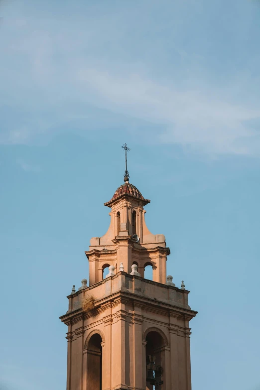 a brown tower with bells stands in a blue sky