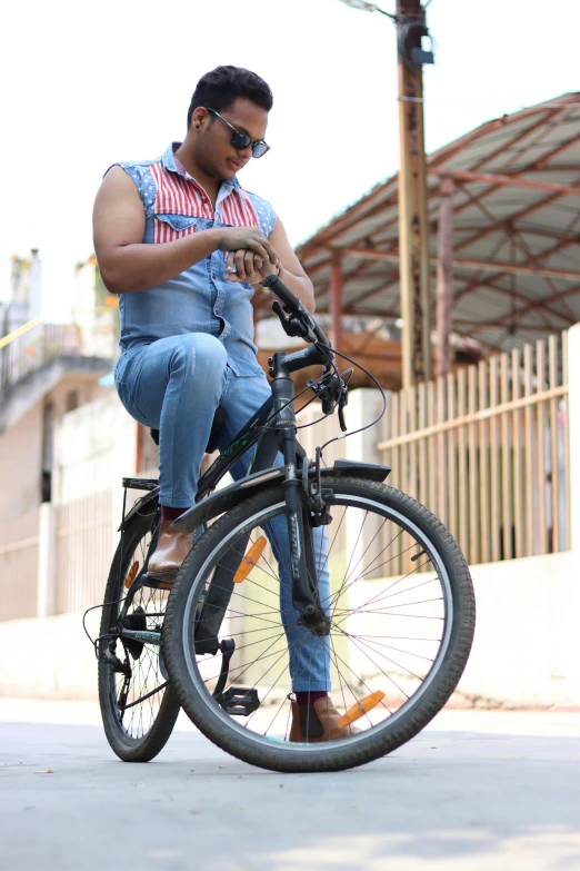 a man wearing glasses on a bicycle checking his phone