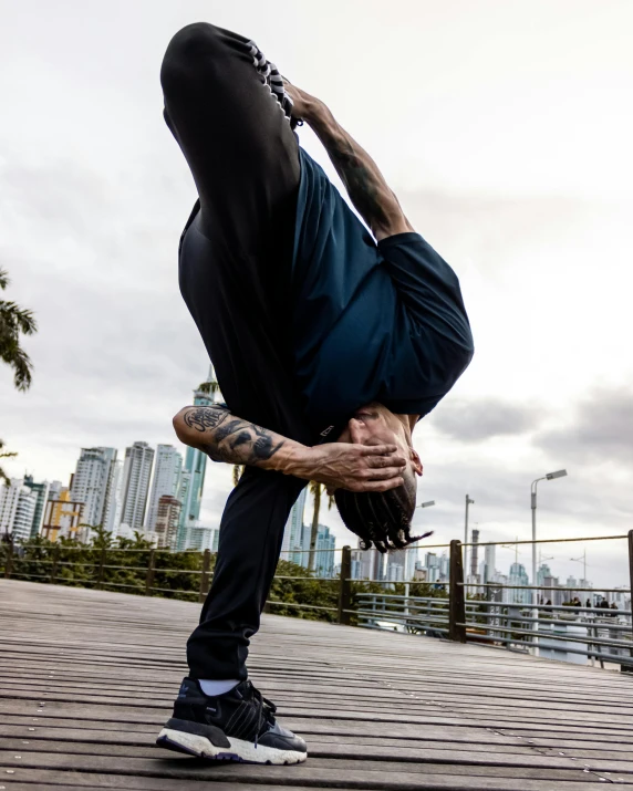 a man with a tattooed head doing a handstand on a pier