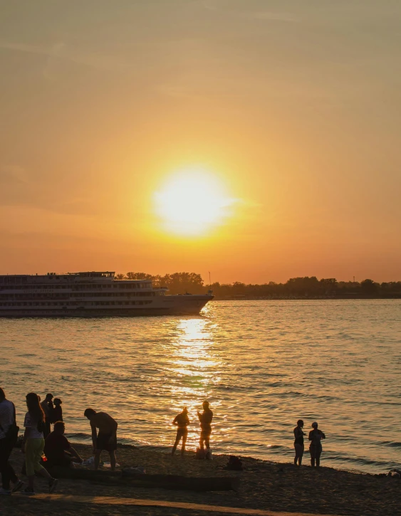 a group of people on the shore watching the sun go down