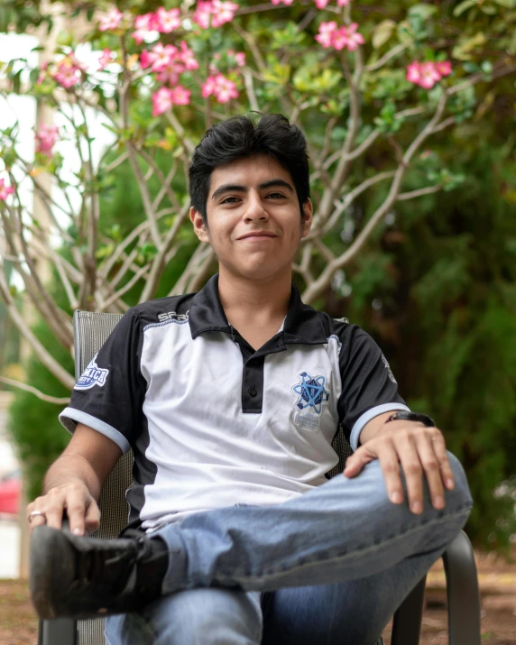 an indian man in a black and white shirt sitting down