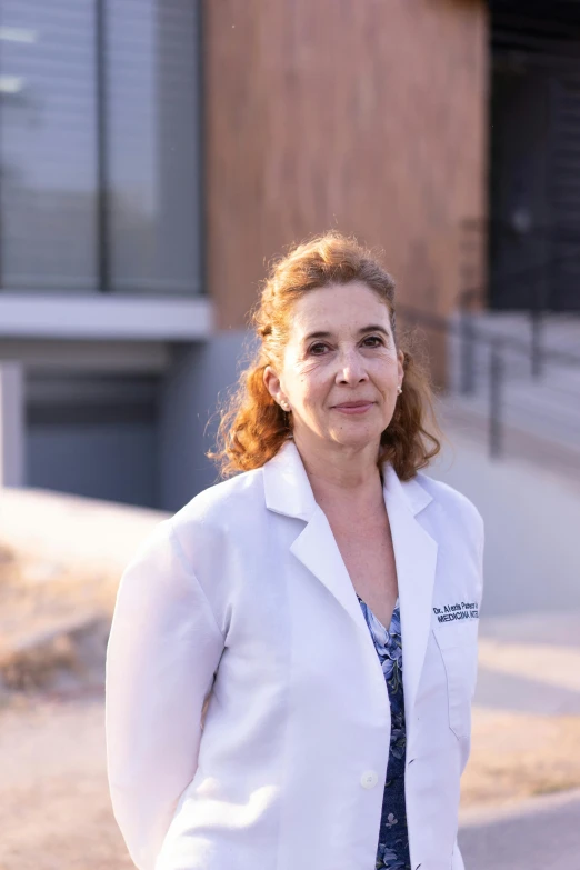 an elderly woman wearing a lab coat standing in front of a building