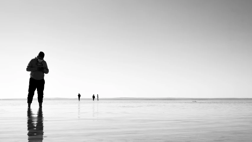 three people standing in the water at the beach