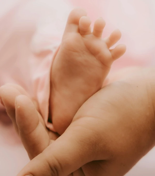 a close - up of someone's hand holding a baby's foot