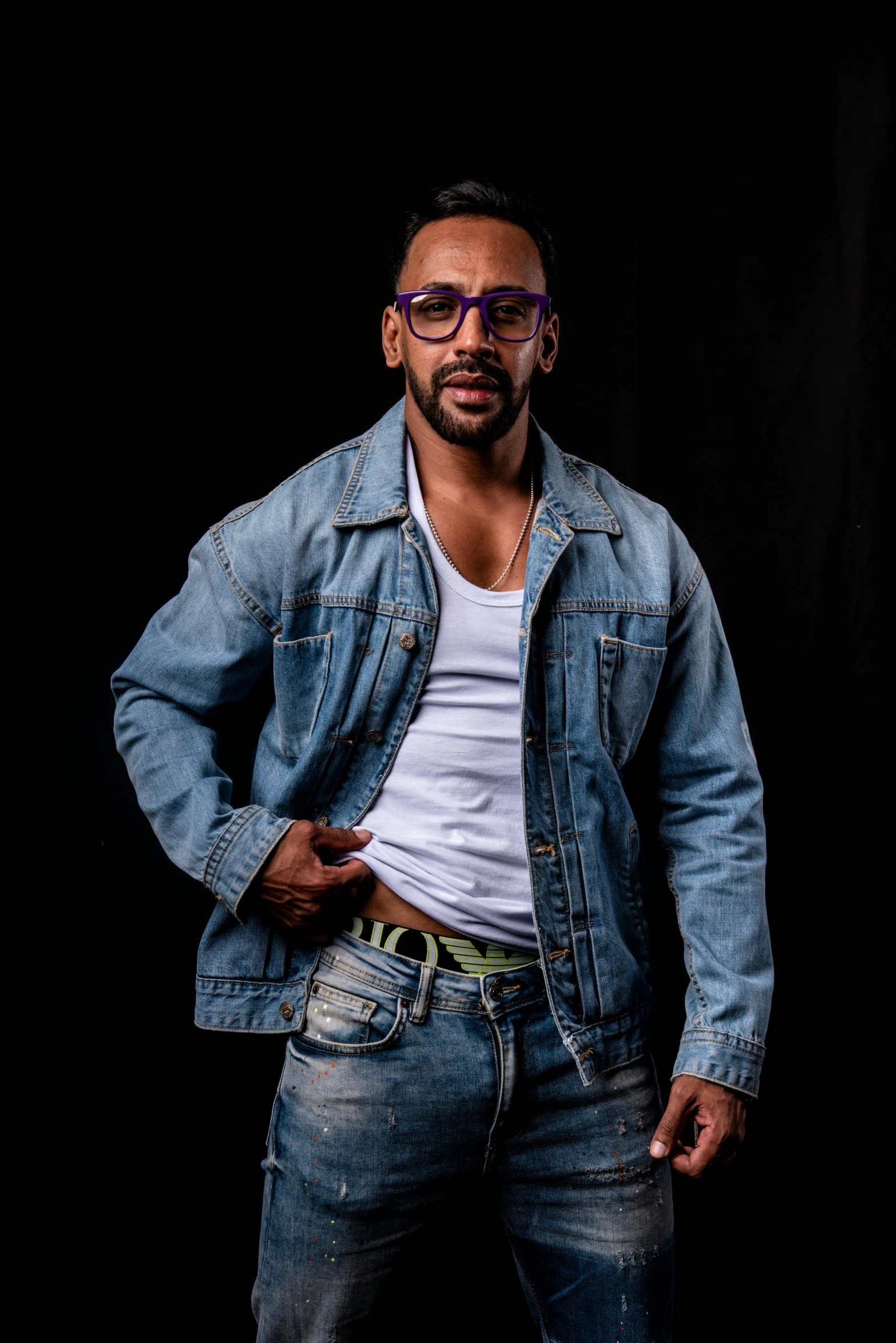 man in denim jacket and glasses posing for a portrait