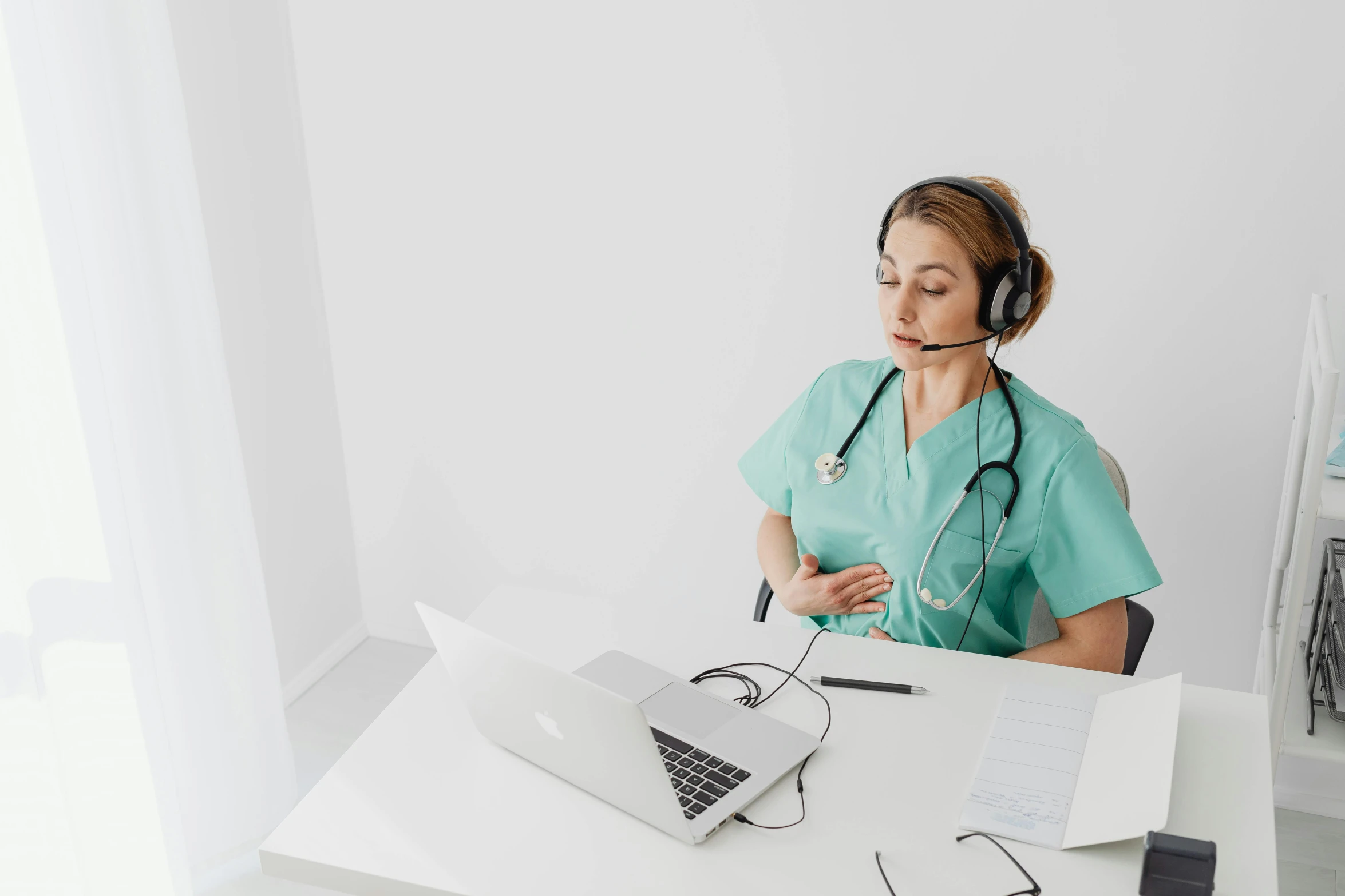 a nurse sitting at a desk with laptops on it