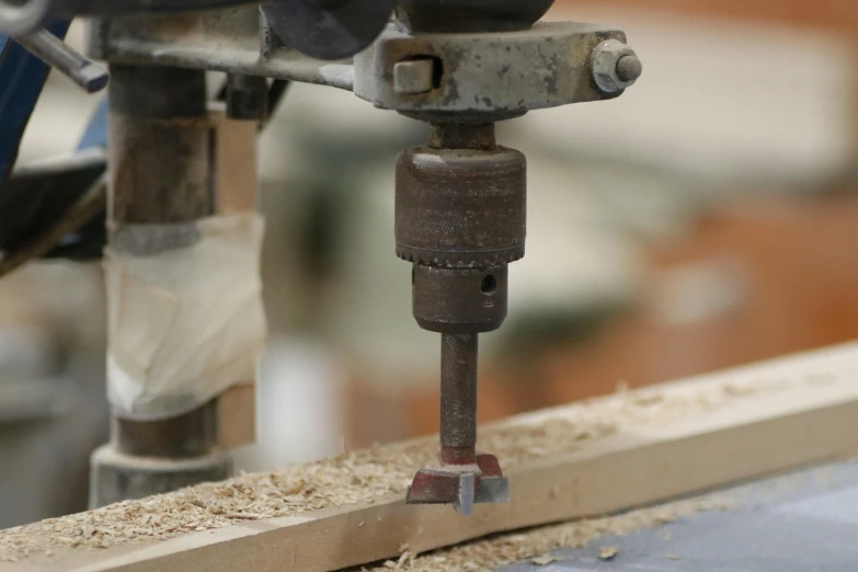 a drill is placed between two holes in an unfinished wood plank