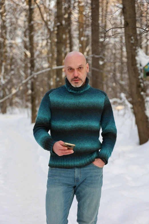 a bald man standing in the snow with a cell phone