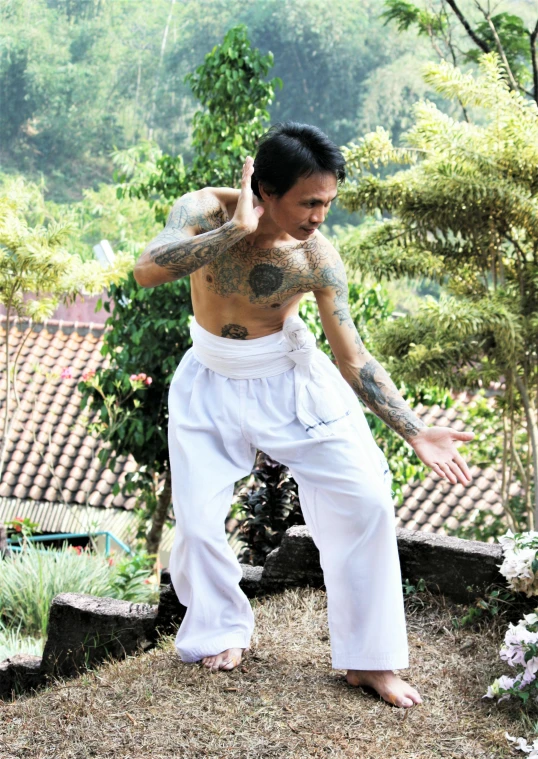 man in white practicing martial technique on hillside