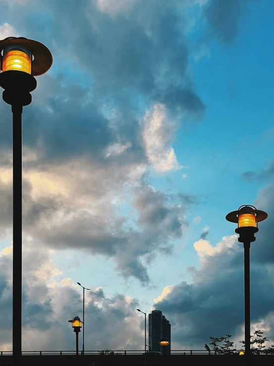 two street lamps against cloudy sky and buildings