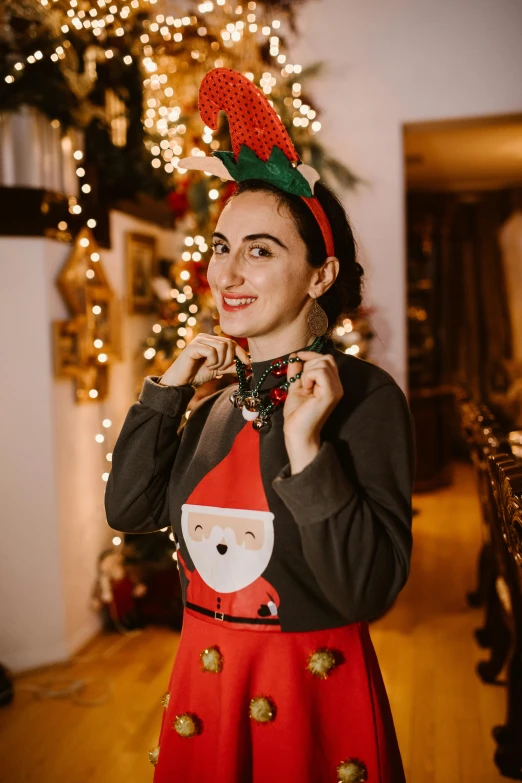 a woman standing in front of a christmas tree wearing an ugly santa sweater