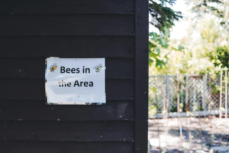 a sign on the side of a house stating that bees in the area are not allowed