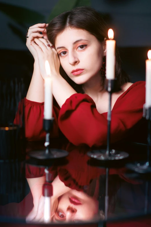 a girl with her hand on her face in front of candles