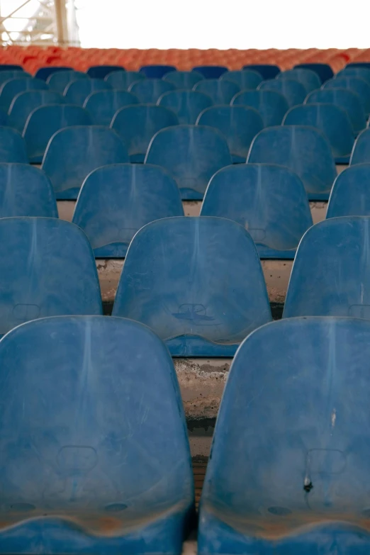 blue seats in stadium with dirt on the ground