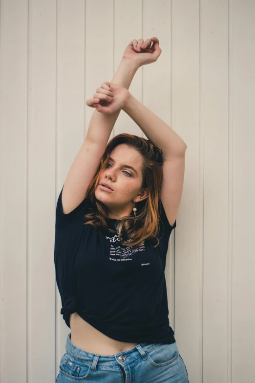 a woman standing next to a wall holding her arm