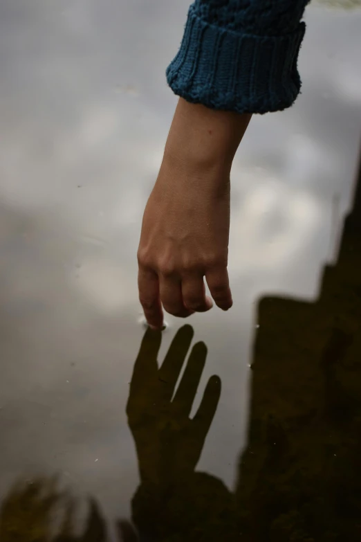 the person holding his hand up in front of a body of water