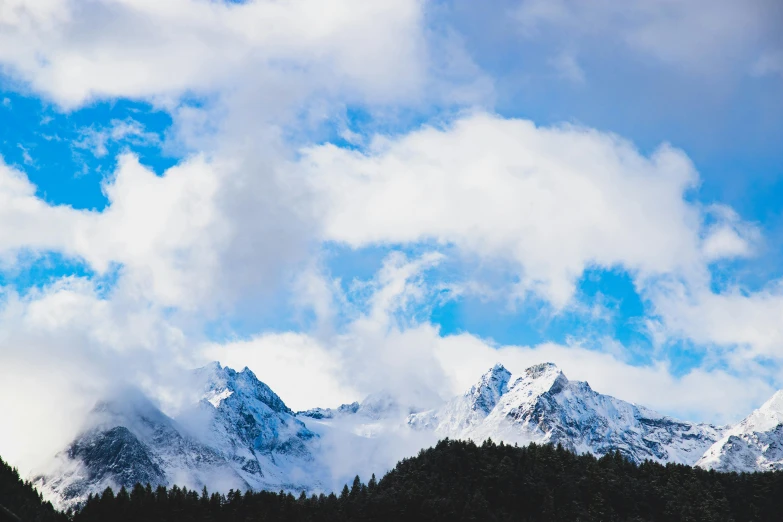 the snow covered mountains with some clouds in the sky