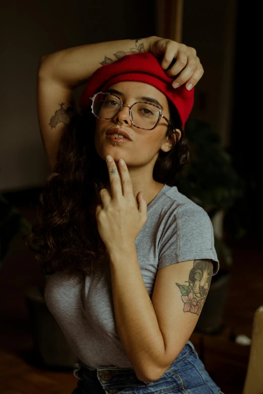 a woman wearing glasses while standing with her arm on her head