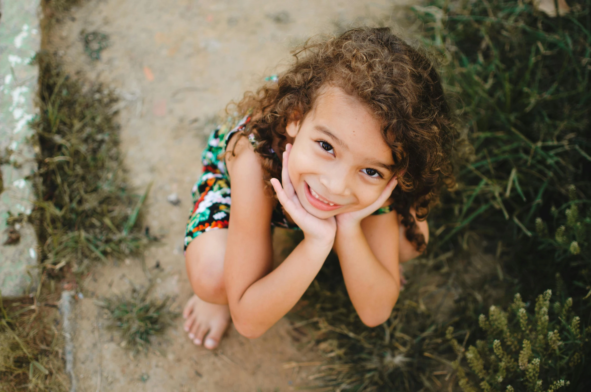 a girl lying in the dirt in front of trees