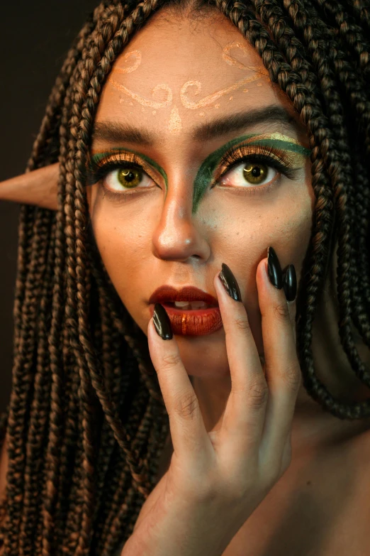 a woman with green makeup and horns holding her fingers to her face
