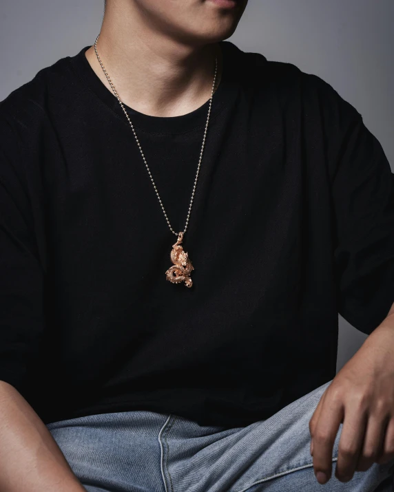 a young man poses in a black shirt and brown necklace