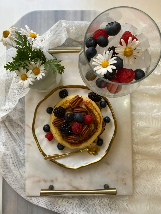 a plate with pancakes, berries, nuts and flowers