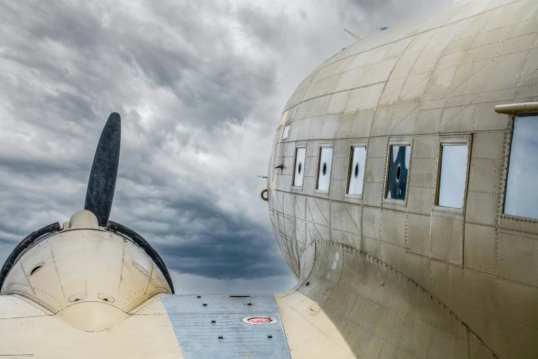 the tail end of an old airplane against a cloudy sky