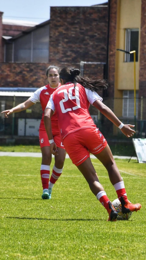 the women are playing soccer in red uniforms