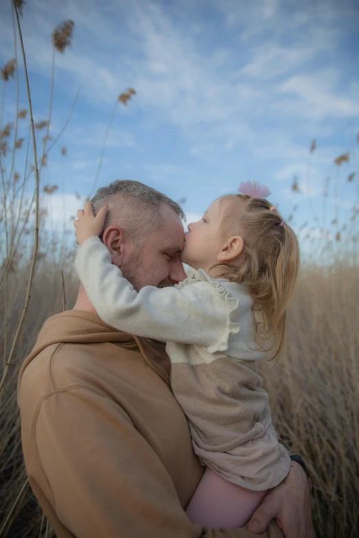 a man holding a small child by his face in a field