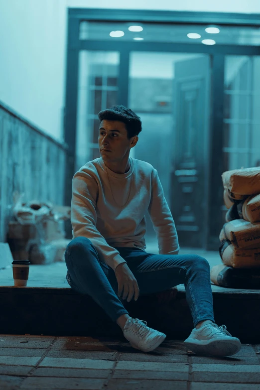 young man sitting on steps in front of stacks of cement bags